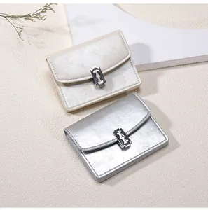 Detalle de carteras de cuero con hebillas metálicas creativas en forma de cuchilla en plata y beige
