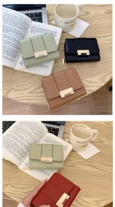Piccoli portafogli in pelle a tre ante per donna in vari colori su tavolo di legno
