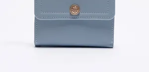 Dettaglio del portafoglio azzurro con chiusura a fiore oro rosa e cuciture di precisione