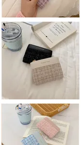 Détail macro du tissu en tweed et du logo doré sur ce porte-cartes zippé pour femmes