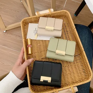 Tre portafogli in pelle beige, verde e nera con eleganti fibbie metalliche dorate