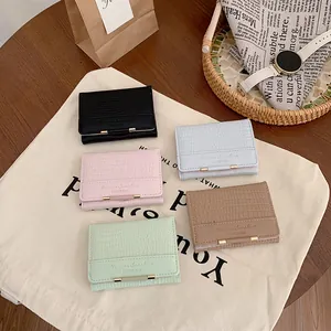 Portafogli corti da donna con stampa coccodrillo in cinque colori su tavolo di legno