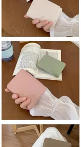 Dettaglio di portafogli in pelle martellata con zip in metallo color crema, rosa e verde