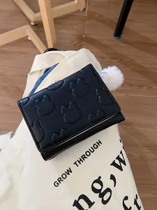 Black short foldable wallet with rabbit ear embossing and white faux fur pompom charm