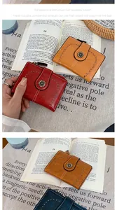 Dettaglio di portafogli vintage in ecopelle con motivi traforati e chiusura a fiore