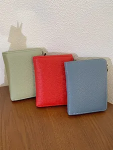 Portafogli in pelle martellata da donna in verde, rosso e blu su un tavolo in legno