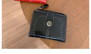 Dettaglio del portafoglio vintage nero con cuciture bianche e un emblema a forma di margherita