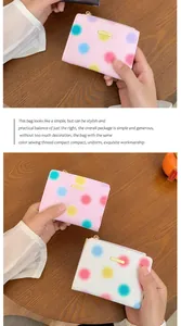 Dettaglio dei portafogli rosa e bianchi con pois colorati e targhetta dorata