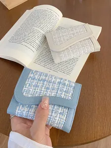 Piccoli portafogli in tweed blu e crema con design intrecciato su un tavolo di legno