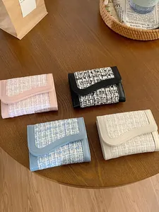 Portafogli corti in tweed in quattro colori con bordi smerlati su tavolo in legno
