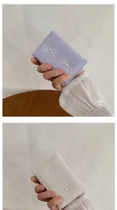 Detail of compact bow wallets with pearl accents in lavender and cream faux leather