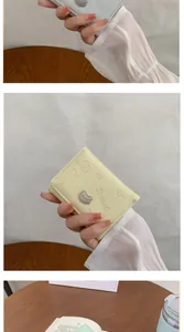 Detail of compact PU leather wallet with embossed bear patterns and metal bear clasp