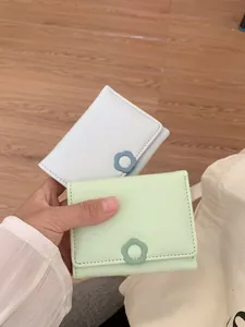 Minimalist tri-fold mini wallet for women featuring a floral clasp in pastel colors