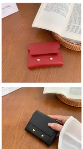 Detail of red and black short wallets with gold accents on a wooden desk setup