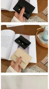 Detail of compact black and cream pebble grain leather wallets with gold stud accents