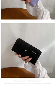 Détail du portefeuille long noir montrant le cuir texturé et le fermoir doré élégant