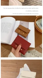 Detail view of small faux leather wallets in burgundy and tan with dual gold snap fasteners