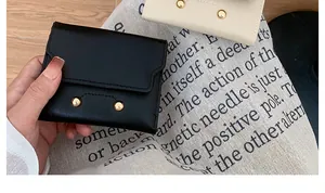Detail of the minimalist leather wallet with smooth texture and golden metal rivets