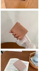 Detail of a pink-brown wrinkled leather folded wallet with a metal zipper and logo patch