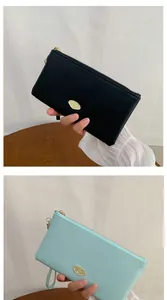 Detail of long leather wallets in black and mint blue with gold metal zip and logo plaque