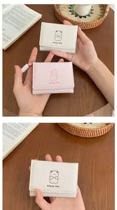 Close-up of cute cartoon bear print and happy day lettering on pastel faux leather wallet