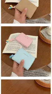 Dettaglio di porta carte in pelle a coccodrillo marrone, rosa e blu con ciondoli di perle