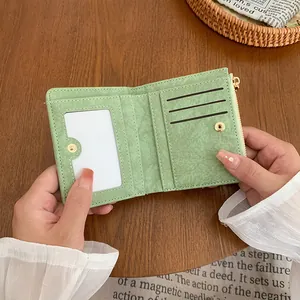 Mint green bi-fold wallet with card slots and zipper on natural wooden surface