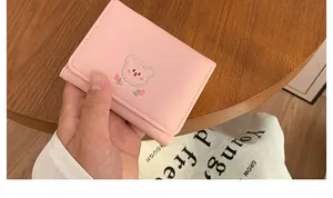 Nahaufnahme einer rosa Mini-Geldbörse mit süßer Bärenstickerei und floralen Details
