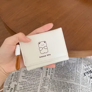 Three-fold white wallet with cute cartoon bear print and lanyard shown on a wooden desk