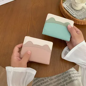 Slim women's bifold wallets with cat ear design in pink and green on a wooden desk