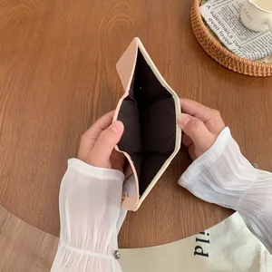 Zweifarbige rosa-beige dreifach faltbare Geldbörse mit Metalldruckknopf in der Hand