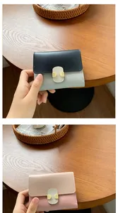 Detailed view of color-blocked short wallets in blue and pink on a rustic wooden table