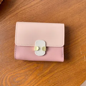 Pink patchwork short women's wallet with gold hardware on a wooden table surface