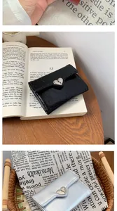 Dettaglio di portafogli pieghevoli in pelle multicolore con fibbie metalliche a cuore argento