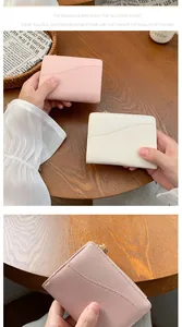 Dettaglio mini portafogli in pelle testurizzata rosa e beige su scrivania in legno