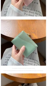 Dettaglio del piccolo portafoglio in pelle verde menta con cuciture fini e zip d'oro