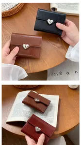 Close-up of vintage trifold wallet with cracked faux leather texture and heart buckle