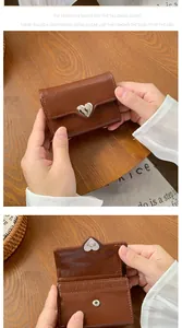 Dettaglio del portafoglio marrone vintage con chiusura a cuore argento e cuciture fini