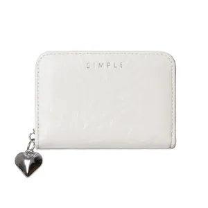 Detail of minimalist cream card holder with heart pendant and crinkle texture leather