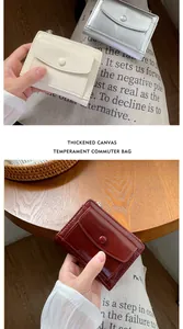 Detail of compact multi-slot wallets in cream, silver, and burgundy textured finish