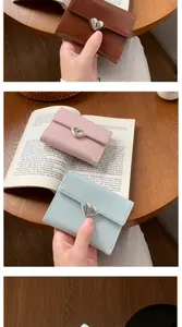 Detailed view of trifold heart wallets in brown, pink, and blue with lychee grain texture