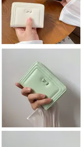 Dettaglio del portafoglio compatto con zip e fiocco in ecopelle bianco crema e menta