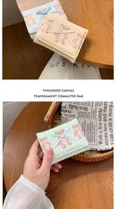 Dettaglio della trama in tela spessa con motivi a orsetto e fiocco elegante sul portafoglio