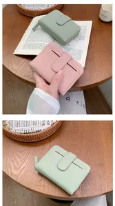Detail of pink and green PU leather short wallets with lychee pattern on wooden desk