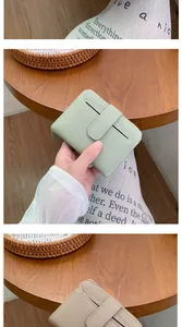 Detail of compact pebbled leather wallets in mint and khaki with buckle and zipper