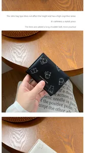 Dettaglio del portafoglio minimalista in pelle nera e beige con stampa di gatti