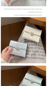 Detail of heart-shaped metal buckle on cream and silver crossbody mini wallets