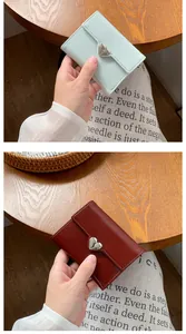 Detailed view of mint green and wine red tri-fold heart wallets on a wooden surface