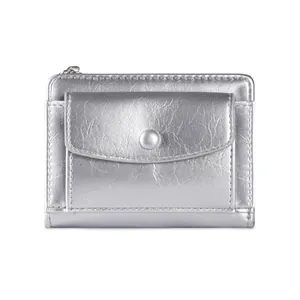 Detail view of silver faux leather wallet featuring a round snap flap and metal zipper