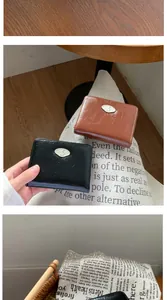Dettaglio di portafogli corti neri e marroni con placca in metallo argentato a forma di S